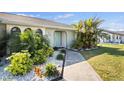 Charming single-story home featuring a beautifully landscaped front yard with lush tropical foliage and a walkway to the front door at 254 Mark Twain Ln, Rotonda West, FL 33947