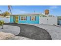 Attractive blue single-story home with paved driveway and fenced-in yard, providing privacy and a pop of color at 539 Shore Rd, Nokomis, FL 34275