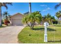 Inviting single-story home featuring a lush front lawn, charming mailbox, and a spacious driveway leading to a garage at 100 Hobo Rd, Rotonda West, FL 33947