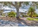 Modest single-story home featuring tropical landscaping with mature trees and shrubs at 295 North Dr, Englewood, FL 34223