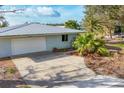 Bright single-story home featuring a metal roof and two-car garage in a tropical landscape at 295 North Dr, Englewood, FL 34223