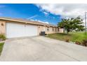 Spacious driveway leading to a two-car garage, complemented by tidy landscaping and a mature tree at 1003 Old Englewood Rd, Englewood, FL 34223