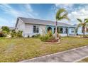 Low angle view of a white house with blue trim and mature landscaping at 13559 Martha Ave, Port Charlotte, FL 33981