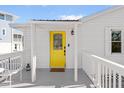 Inviting front porch featuring a bright yellow door, white railings, and charming decor at 205 Sand Dollar Ln, Englewood, FL 34223