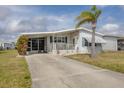 Well-maintained single-story home with carport, a lush lawn, and tropical palm tree at 8436 Buttonquail Dr, Englewood, FL 34224