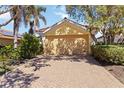 Exterior view of a home with a two-car garage, terracotta roof, and a brick driveway at 10508 Crooked Creek Dr, Venice, FL 34293