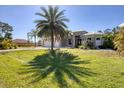 Charming single Gathering home with a well maintained lawn, a three-car garage, and lush palm trees at 14157 Kewanee Ln, Port Charlotte, FL 33981