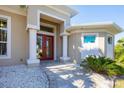 Close up view of the front door and entryway with stately columns and stone landscaping at 14157 Kewanee Ln, Port Charlotte, FL 33981