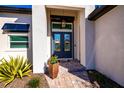 Close-up of a modern glass double-door entry, complemented by vibrant plants and a stylish hanging lantern at 14718 San Domingo Blvd, Port Charlotte, FL 33981