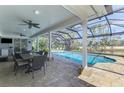 Inviting screened-in pool area with covered patio, ceiling fans, dining furniture, and views of the water at 17 Dominica Dr, Englewood, FL 34223