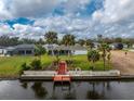 View of home's backyard with a canal, dock, palm trees, and green lawn at 184 Eppinger Dr, Port Charlotte, FL 33953