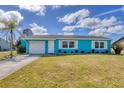 Charming turquoise home featuring a white garage door, front door, white trimmed windows, and a manicured front lawn at 6264 Drucker Cir, Port Charlotte, FL 33981