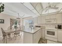 Bright kitchen and dining area with white cabinets, a chandelier, and sliding glass doors to the exterior at 6699 San Casa Dr # Q3, Englewood, FL 34224