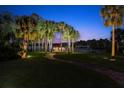 Scenic backyard view with a waterside pavilion, surrounded by palm trees and a brick walkway at twilight at 790 N River Rd, Venice, FL 34293