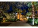 Stately home with manicured landscaping, trees, and winding walkway, beautifully illuminated at night at 790 N River Rd, Venice, FL 34293