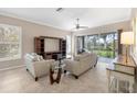 A sunlit living room features tile floors, a ceiling fan, and sliding glass doors to the lanai at 8356 Creekview Ln, Englewood, FL 34224