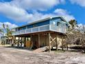 Coastal home elevated on stilts, featuring wood supports, a charming balcony and a private outdoor space at 8694 Marsh St, Placida, FL 33946