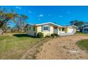 Angle view of a light yellow single-story home, showcasing the front and side yards at 91 Beverly Cir, Englewood, FL 34223