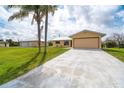 Spacious home featuring an attached two-car garage, a long driveway, and well-maintained landscaping at 10075 Bentley Ave, Englewood, FL 34224