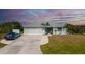 Charming one-story home with a well-manicured lawn, two car garage, and an American flag flying proudly at 14382 Lillian Cir, Port Charlotte, FL 33981