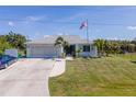 Charming single-story home featuring a well-maintained lawn, two-car garage, and an American flag at 14382 Lillian Cir, Port Charlotte, FL 33981