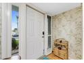 Bright and airy entryway with white door, leafy wallpaper, and a charming wicker shelf at 1461 Aqui Esta Dr # B3, Punta Gorda, FL 33950
