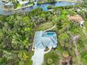 Aerial view of home with a private pool, surrounded by lush landscaping and a curving driveway at 150 N Oxford Dr, Englewood, FL 34223