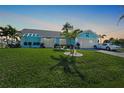 Charming blue home with well-manicured lawn, palm trees, and a classic white Corvette in the driveway at 15652 Ruston Cir, Port Charlotte, FL 33981