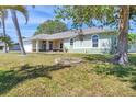 Lush front lawn surrounds home with a well-kept exterior with painted accents and shade tree at 224 Pine Glen Ct, Englewood, FL 34223