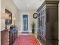 Inviting foyer with elegant furnishings, a decorative mirror, stylish lamps, and a patterned red rug at 23781 Waverly Cir, Venice, FL 34293