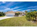 Charming single-story home with a well-manicured lawn, palm trees, and a two-car garage at 48 Par View Ct, Rotonda West, FL 33947