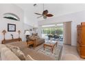 Inviting living room featuring tile flooring, ceiling fan, and sliding doors to the screened-in lanai at 48 Par View Ct, Rotonda West, FL 33947