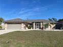 Charming single-story home with a well-manicured lawn, beige exterior, and screened front entry at 5262 Weatherton St, North Port, FL 34288