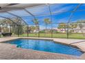 Inviting screened-in pool area featuring brick pavers and lush landscaping, perfect for relaxation at 59 Long Meadow Ln, Rotonda West, FL 33947
