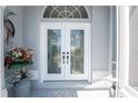 Elegant double front door with decorative glass panels, sidelight, arched window, and stylish exterior decor at 10308 Euston Ave, Englewood, FL 34224