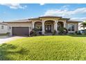 Beautiful home exterior featuring a manicured lawn, arched entryway, and attached two car garage at 15578 Seafoam Cir, Port Charlotte, FL 33981