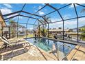 Inviting screened-in pool area with lounge chairs, lush landscaping, and a canal view with boat dock at 15578 Seafoam Cir, Port Charlotte, FL 33981