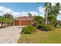 Inviting single-story home boasts a brick paved driveway, mature palms, and verdant landscaping at 16137 Alcira Cir, Punta Gorda, FL 33955