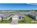View of a single Gathering home showcasing its well-manicured lawn, brick driveway, and serene lake view at 5132 Schubert Trl, North Port, FL 34287
