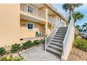 Condo exterior with stairs leading to a covered landing featuring a bright teal chair at 6610 Gasparilla Pines Blvd # 111, Englewood, FL 34224