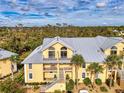 Yellow condo building with balconies and metal roof set amongst lush green trees at 6610 Gasparilla Pines Blvd # 111, Englewood, FL 34224