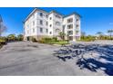 Scenic building exterior with balconies and a parking lot surrounded by manicured landscaping at 9203 Griggs Rd # 204, Englewood, FL 34224