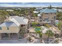 Expansive aerial view of a stilt home with a backyard pool, deck, and cabana, surrounded by lush tropical landscaping at 97 Kettle Harbor Dr, Placida, FL 33946