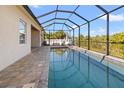 A luxurious screened in pool featuring beautiful neutral toned brick pavers surrounding the pool at 10498 Bay State Dr, Port Charlotte, FL 33981