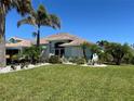 Inviting single-story home with lush landscaping, mature palm trees, and well-manicured lawn at 108 Fairway Rd, Rotonda West, FL 33947