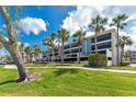 Beautiful view of condo exterior complemented by swaying palm trees and well-manicured lawn at 1651 Beach Rd # 311, Englewood, FL 34223