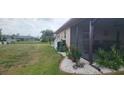 Backyard featuring a screened patio, well maintained lawn, and decorative landscaping at 171 Caddy Rd, Rotonda West, FL 33947