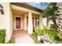 Welcoming front porch featuring red door and shutters, neutral columns, and seating area at 2628 Sherman Oak Dr, North Port, FL 34289
