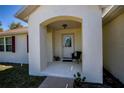 Inviting front porch with a chair, potted plants, and an arched entryway at 6368 Pennell St, Englewood, FL 34224