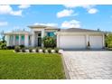A contemporary home featuring a three-car garage, lush lawn, and mature landscaping at 10491 Sarasota Rd, Port Charlotte, FL 33981